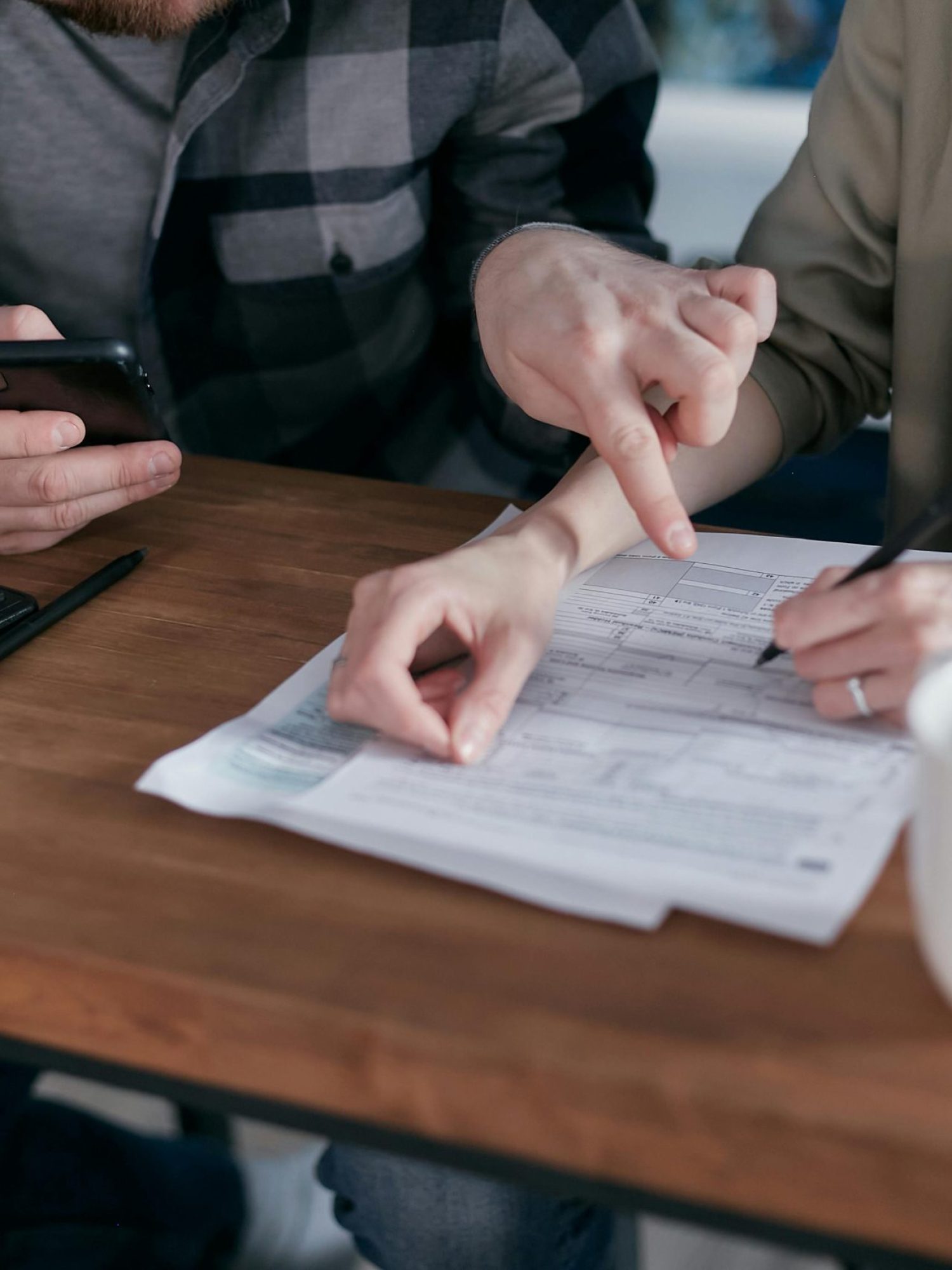 A couple analyzing financial documents and using a calculator at a home table.